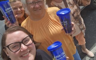 UCHRA Public Transportation employees pose with blue tumblers, featuring the UCHRA Public Transportation logo.