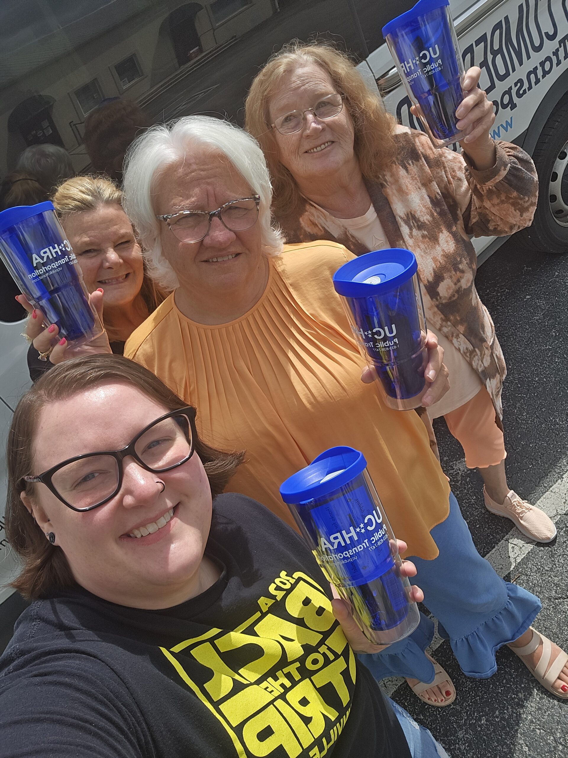UCHRA Public Transportation employees pose with blue tumblers, featuring the UCHRA Public Transportation logo.